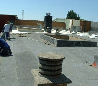 Trabajadores aplicando productos impermeabilizantes en cubierta de un edificio