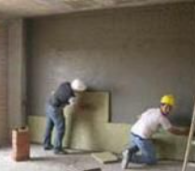 Dos trabajadores instalando paneles aislantes en la pared de una habitación